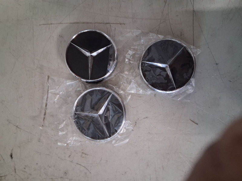 Three Mercedes star wheel center caps with black faces and chrome-look trim